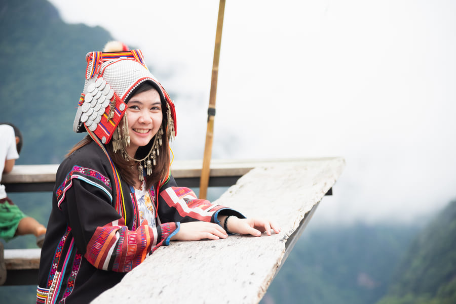 mujer asiatica sonriendo, la mujer usa un poncho color negro y un gorro color blanco